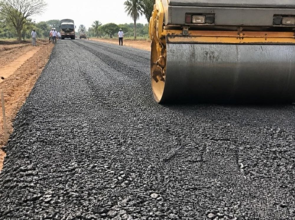 Wet mix macadam road base layer being rolled on a road under construction